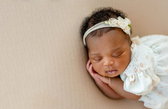 African American newborn baby sleeping head on her hands