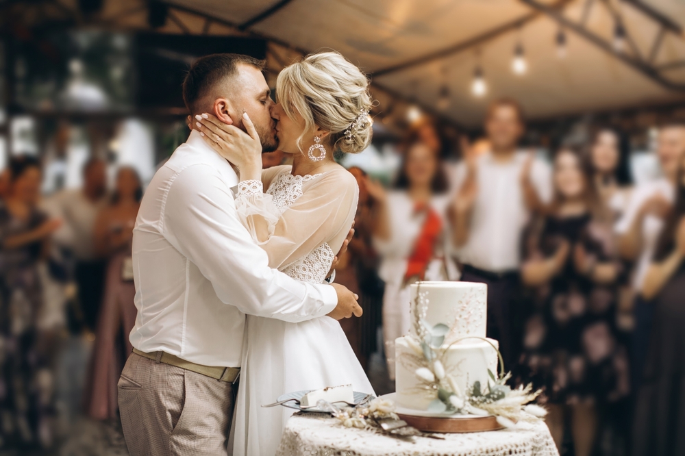 bride and groom kiss by the wedding cake