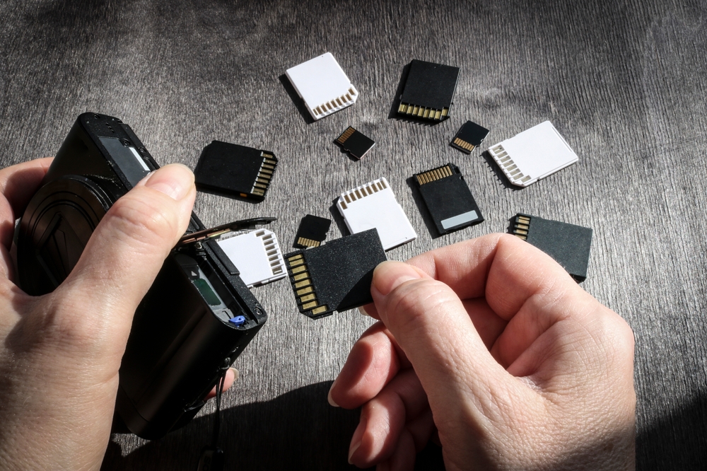 Close-up of hands inserting an SD card into a camera's memory slot