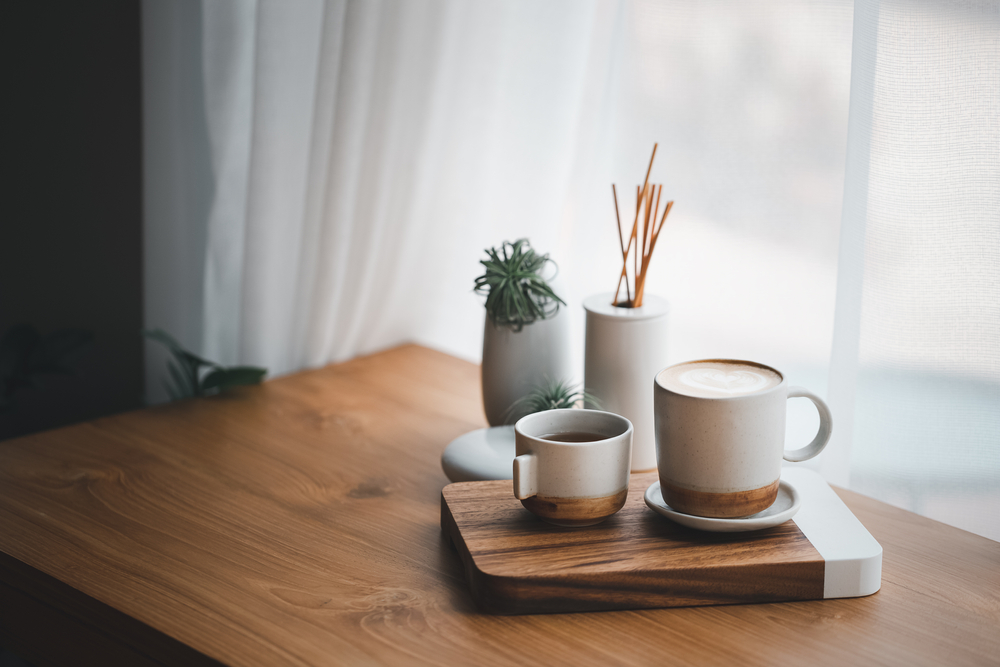 cup of hot coffee and tea on wood table besides window