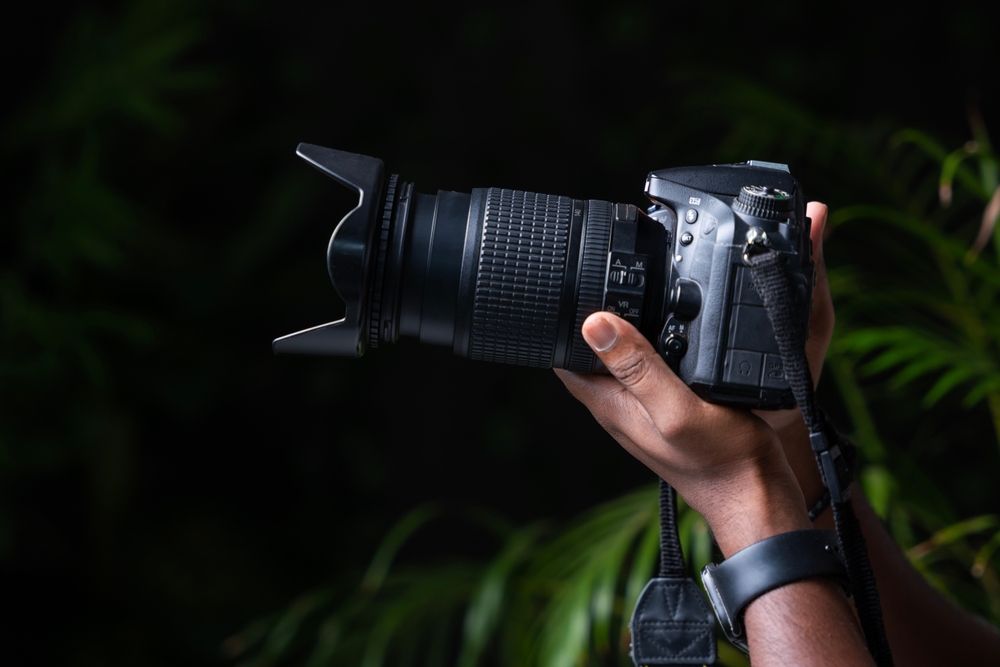 Hand holding camera dark background