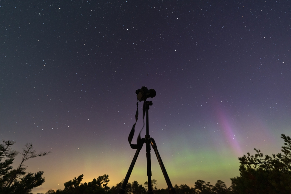 mirrorless camera on a tripod during the northern lights and star filled sky