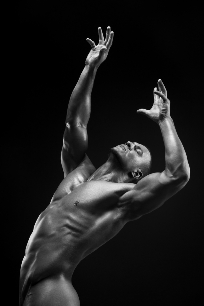 naked man posing in the studio on a dark background BW