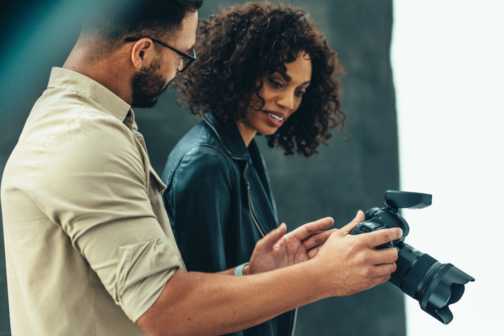People looking at the back of a camera talking about photos 