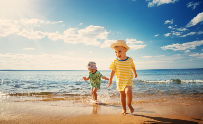 small boy and girl playing on the beach on summer holidays