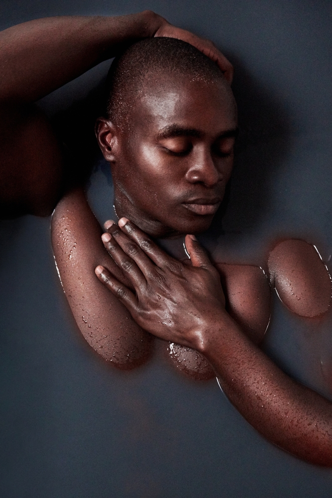 young man submerged in a bath filled with dark water